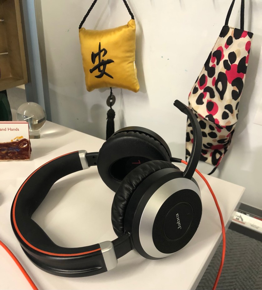 headphones on a desk, with a mask and a peace pillow in Japanese.